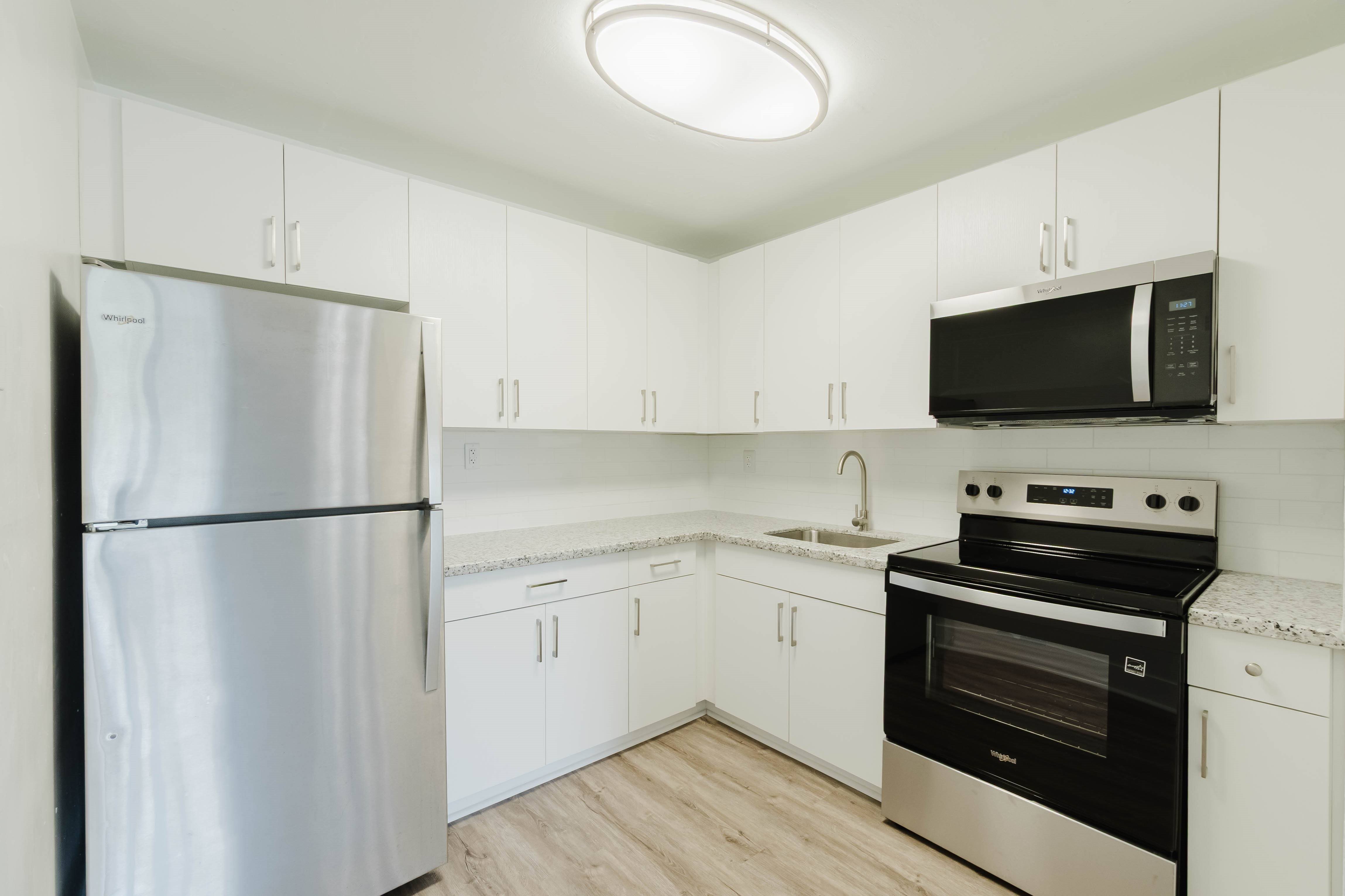 A kitchen with a refrigerator, oven, and microwave.,A kitchen with a refrigerator, oven, and microwave.